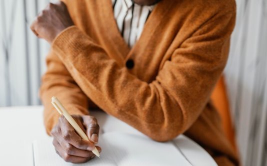 A man writing in a notebook at a table